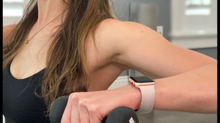Woman using smartwatch during Pilates workout at Charleston studio.