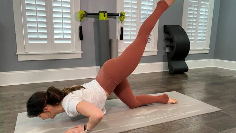 Woman doing a leg lift exercise on a Pilates mat during a workout session.