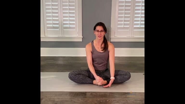 Experienced Pilates instructor demonstrating seated stretch for flexibility.