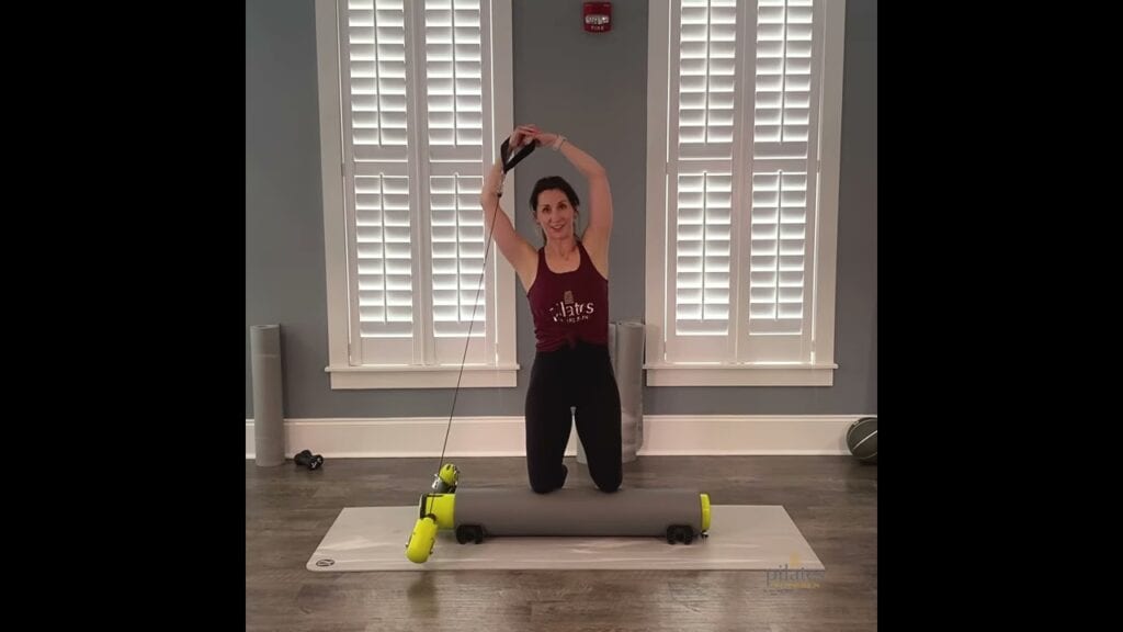 Woman demonstrating use of Pilates roller and resistance bands at Pilates of Charleston.