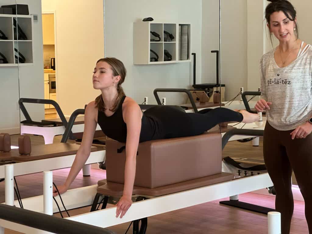 Instructor coaching a client on the reformer at Pilates of Charleston