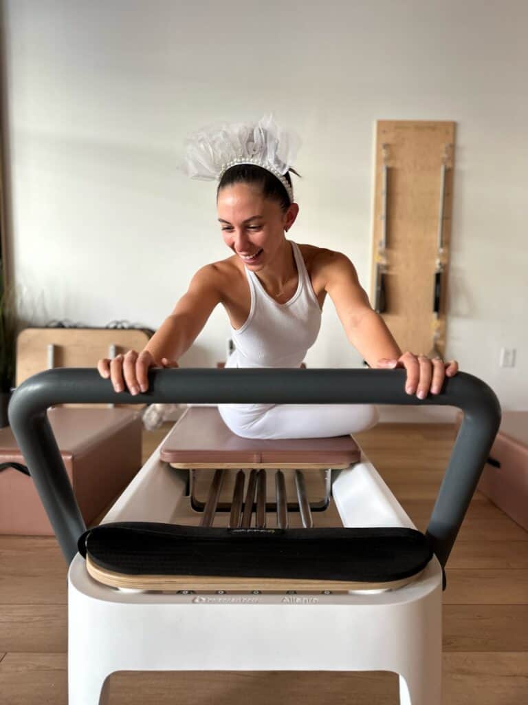 Relaxed woman performing Pilates on reformer machine at a boutique studio.