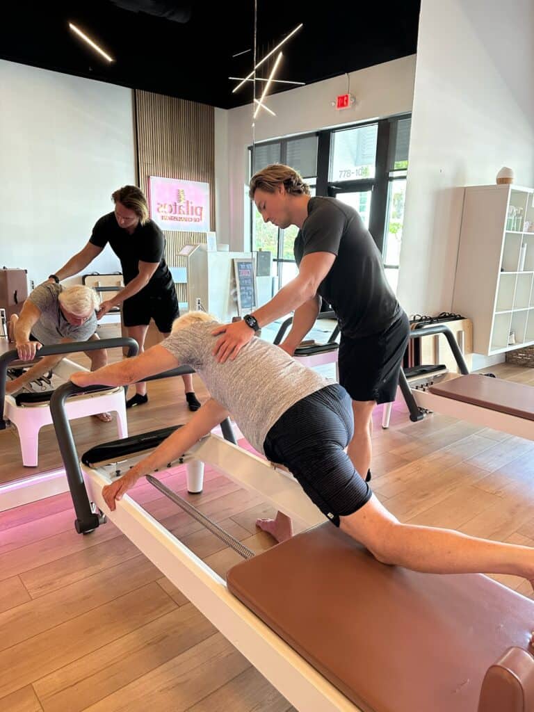 Elderly woman practicing Pilates on reformer machine at Charleston studio with instructor.