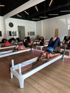 Pilates reformer workout session with clients engaging core muscles in a modern studio.