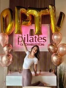 Vibrant image showcasing a woman celebrating at Pilates of Charleston with balloon decor.