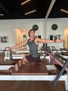 A woman practicing Pilates on reformer machine at Pilates of Charleston gym studio.