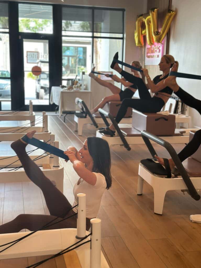 Women performing Pilates exercises on reformers at a trendy fitness studio.